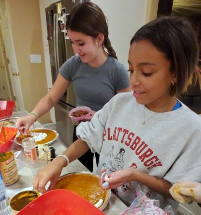Haley Olstein and Skylar Shaw, both of Monroe, enjoy cooking food for seniors at the CTeen Thanksgiving cook-off.