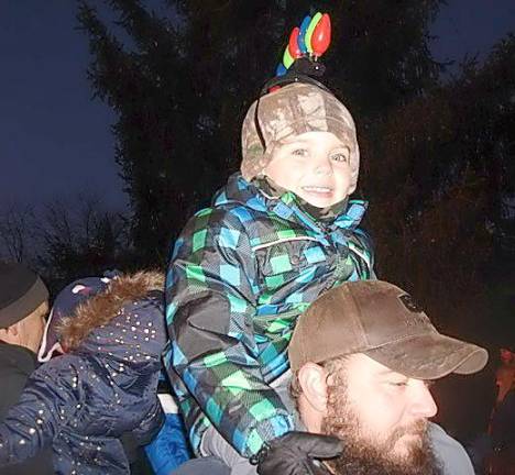 Gunner Conklin, 5, is all lit up to celebrate the season! Here he is on dad’s shoulder to get a good view of Santa. Gunner attended the tree lighting ceremony with his mom, Katie, and his dad, Mike. “Gunner’s been talking about the tree lighting all week and looking forward to coming. He’s been counting down the days for two weeks now. He loves wearing the lights,” said his Mom.