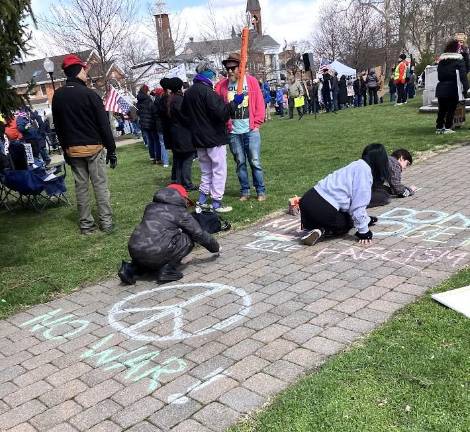 Rally attendees write messages in chalk.