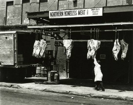 A worker hauls product from a Meatpacking District purveyor on Washington Street into a waiting truck in this photograph by Eugene Gordon. Photo courtesy of New-York Historical Society.