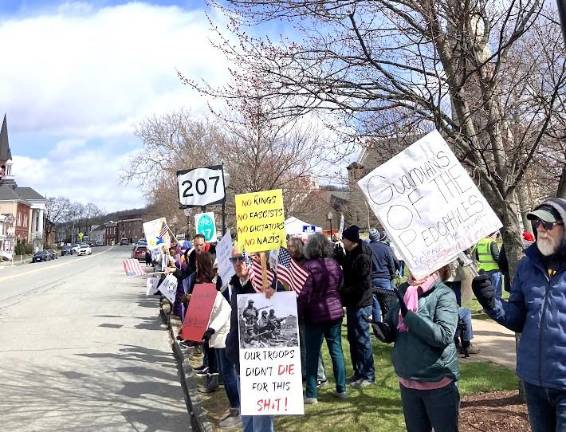 No Kings participants hold signs criticizing Trump administration,