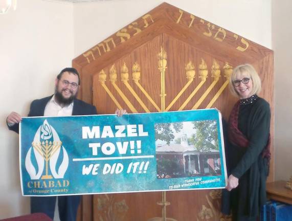 Rabbi Meir Borenstein and Diane Greenwald with their celebration sign.