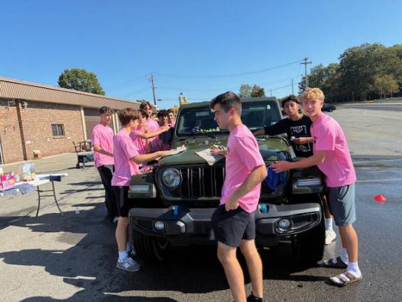 Soccer players Gio Hernadez-Leon, Myles Warren, Timothy Papa, Jonathan Labush, Dylan Fleming, Sean Connell, Cole Frazier, Logan Diglio, and Arav Patel dry off a car Sunday morning at the school district bus garage.