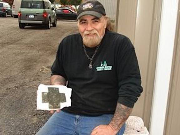 Daniel Aneiros holds the Spanish-American War medallion that he found on Pumpkin Swamp Road. He's searching for the owner. (Photo by Geri Corey)