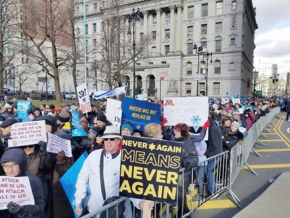 Richard Fuchs marches with a Never Again Means Never Again sign.