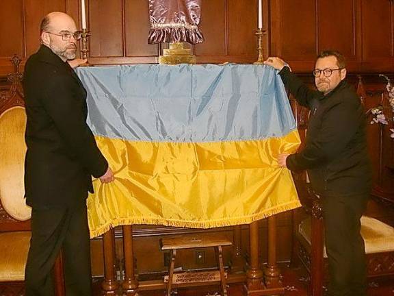 Robert Person, (l), and Peter Kosciolek (r) arranged the Ukrainian flag on the church chancel before the prayer