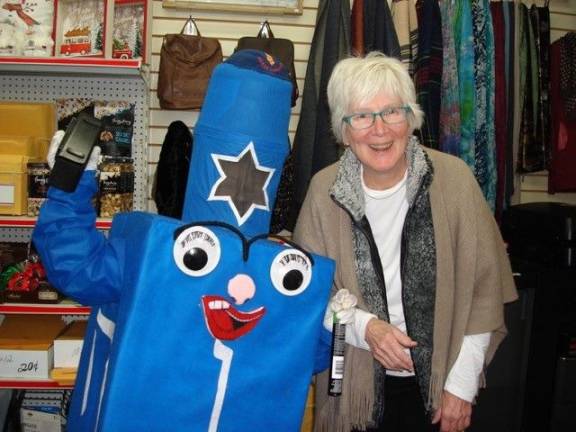 Linda Mabie, owner of Linda&#x2019;s Office Supply on Main Street in Goshen, poses with a happy, life-sized dreidel, which seen on the streets of downtown Goshen, adding to the festivities (Photo by Geri Corey)