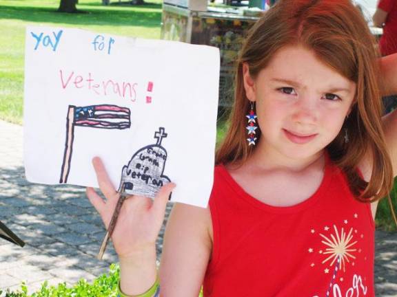 Josie Cannela, 8, with a sign she drew for the parade. She was watching the festivities with her mom, Colleen Cappadora, who noted that her daughter “is very creative.”