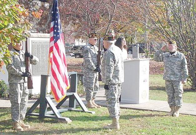 The rifle bearers stand guard as Lauren Luck sings the national anthem at the Veteran’s Day observance in Goshen. Commander Ray Quattini salutes the American flag.