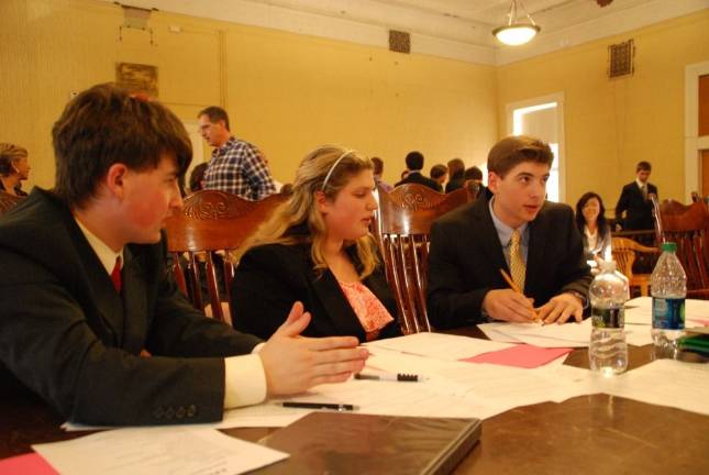 Young Goshen attorneys Elijah Knowlton, Emily Shapiro and Daniel Solomon in a huddle preparing points for trial. (Photo by Ed Bailey)