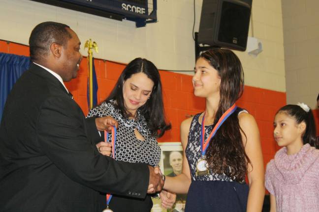 Emily Deserto is congratulated by SUNY Orange Vice President of Student Services Paul Broadie II. She is followed by Carolina Cruz.