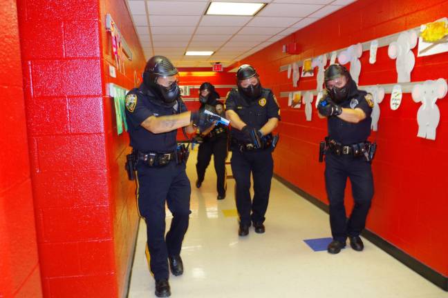 With weapons drawn, four Vernon, N.J., Township police officers walk down the main hall at Walnut Ridge Primary School during a drill this past August searching for three active shooters in the school and two hostages being held in a classroom (Photo by Chris Wyman)