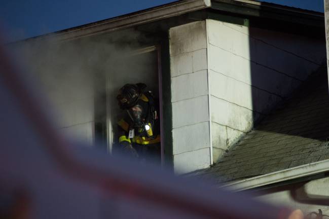 Goshen, NY Jan 13 2018. Firefighter in breathing apparatus inspects the inside of the smoke filled building