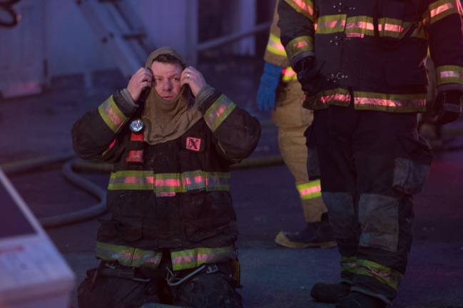 Goshen, NY Jan 13 2018. Firefighter removes his breathig gear after inspecting the inside of the burnt building