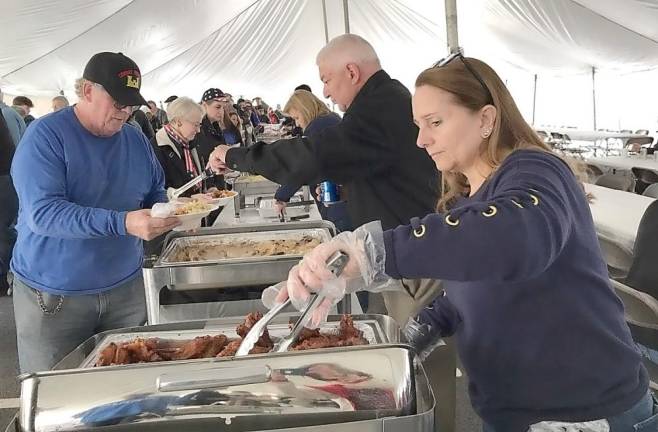 Suresky's Auto general manager Jeff Musumeci and his wife, Jennifer, take a turn on the serving line to feed the hundreds of veterans who turned out for this year's celebration.