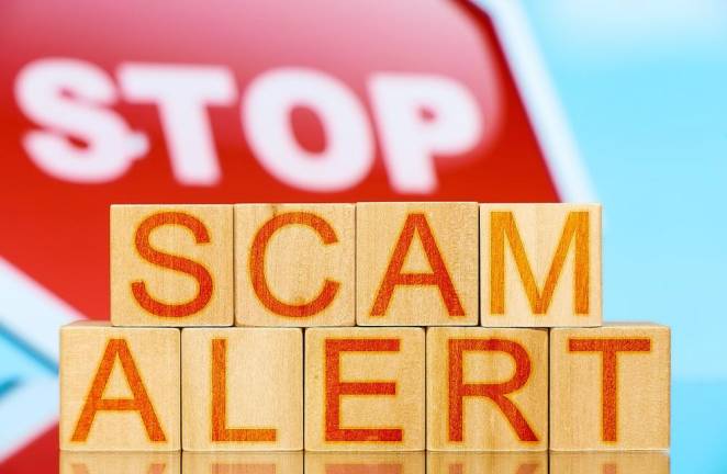 scam alert. wooden blocks with scam alert lettering and stop sign on background
