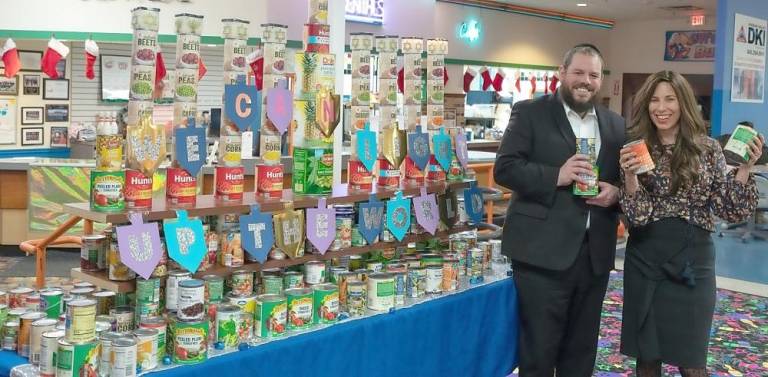 Rabbi Pesach and Chana Burston beside the “Can-orah” made of donations of canned foods at Chabad’s Hanukkah celebration in Chester. The cans were donated to families in need.